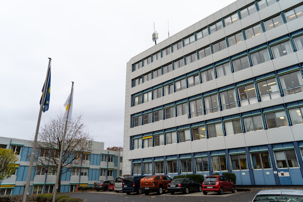 Parkplatz der Klinik Wingertsberg, mit hängenden Flaggen und Klinikgebäude 